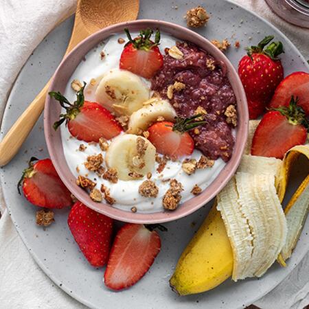 bowl of yogurt and fruit with a banana and strawberries