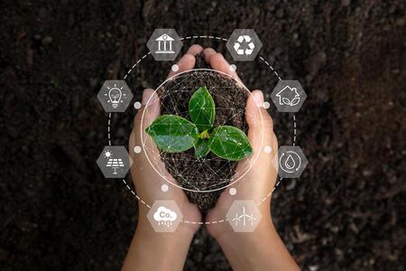 hands holding soil with a plant with a graphic overlay of icons of recycling, renewable energy, CO2