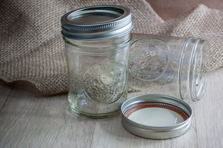 Some glass jars with medal lids in front of some burlap