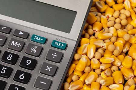 Up close view of a calculator laying next to corn kernels and soybeans.