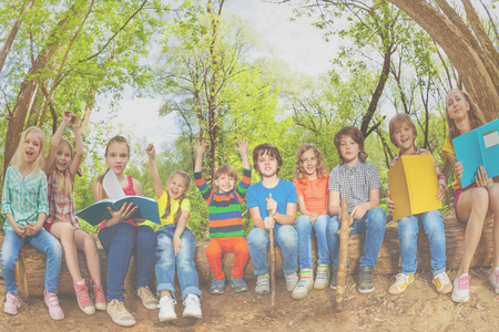 10 kids sitting on a log outside