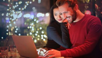A couple smiling while looking at a laptop
