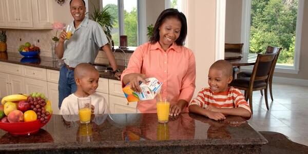 mother pouring orange juice for children