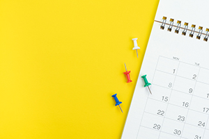 calendar and pushpins on yellow background