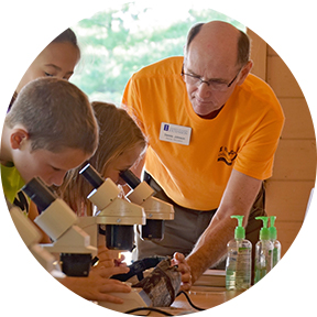 volunteer assisting youth looking through microscopes