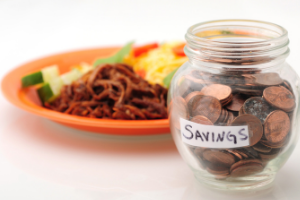 Plate of food with jar of pennies labeled "savings"