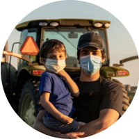 man and boy wearing masks in front of farm equiptment