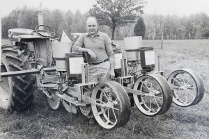 man standing in front of old tractor equipment