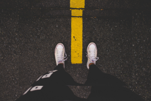 Feet in white canvas shoes on each side of a yellow line