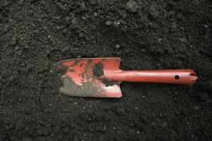 red trowel sitting on soil