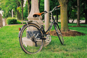 Bicycle propped against light post in the grass at park 