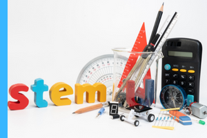 the word stem on a desk. protractor, compass, magnet in a beaker with a calculator, compass, eraser, and pencil laying around it.