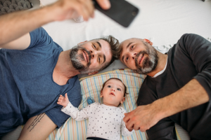 Two middle aged men taking a selfie with their baby