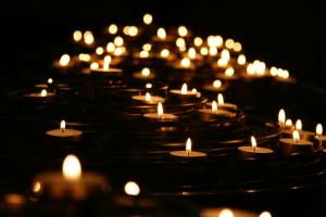 several dozen lit small candles on dark background