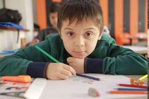 young child in school with colored pencils and paper