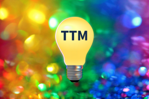 colorful rainbow background with a yellow lightbulb and the letters TTM