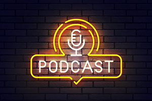 Neon yellow and white podcast sign with microphone on brick wall