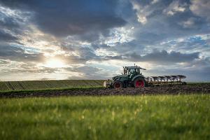 A tractor driving through a field near sunset