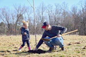 a man and little girl planting an oak tree