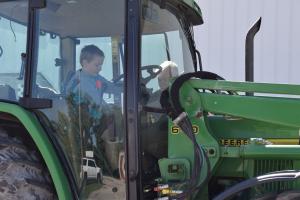 little boy in a big green tractor with cab