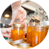 hand screwing on lid of glass jar filled with peach preserves