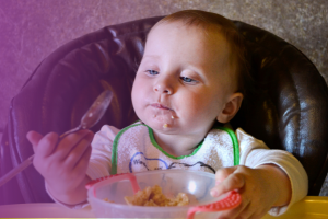 toddler eating food out of a bowl