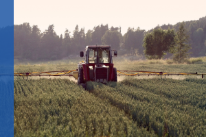 tractor with a sprayer spreading chemicals over a crop