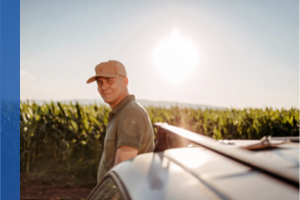 farmer standing between his corn crop and a vehicle
