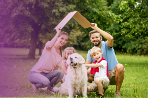 family outside in the grass holding a piece of angled cardboard above their head like a roof