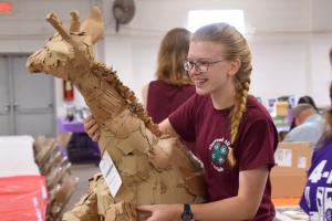 girl holding a 4-H visual arts project, paper machae giraffe