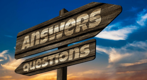 Sign with "answers" pointing one direction and "questions" pointing opposite direction with sky and clouds in background