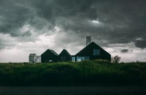 Farmhouse with black storm clouds overhead