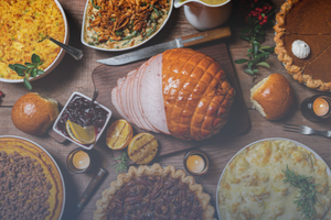 A Thanksgiving table filled with sliced ham, pumpkin pie, and green bean casserole.