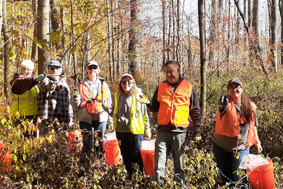 volunteers with orange buckets in forest