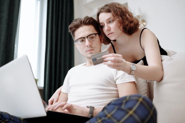 Woman and man looking at credit card and laptop