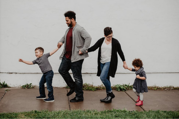 A family walks down a rainy sidewalk.