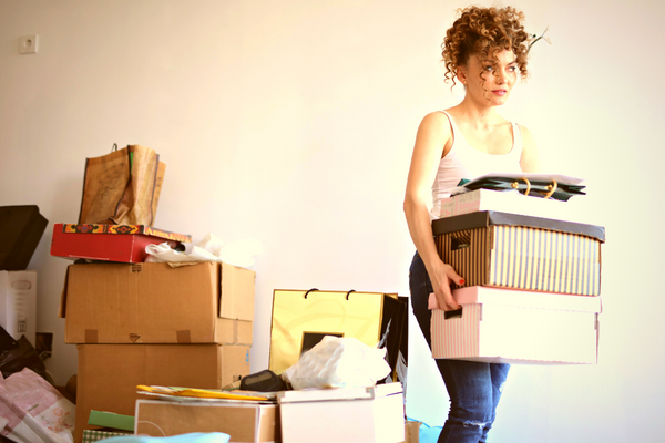 Woman carrying boxes in cluttered room