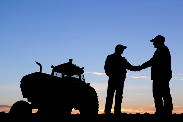 Tractor and 2 farmers shaking hands.