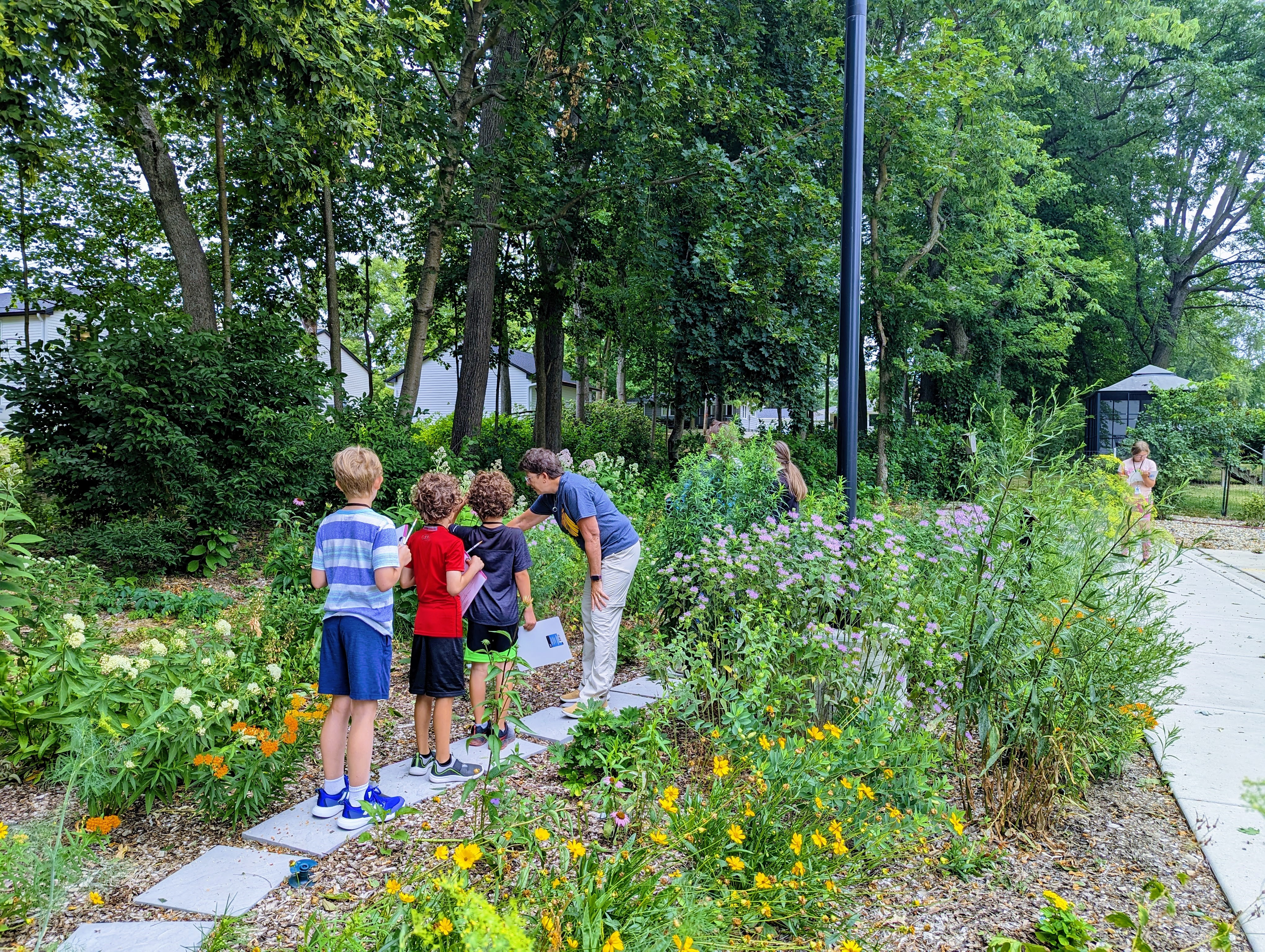A woman talks to children in a native garden