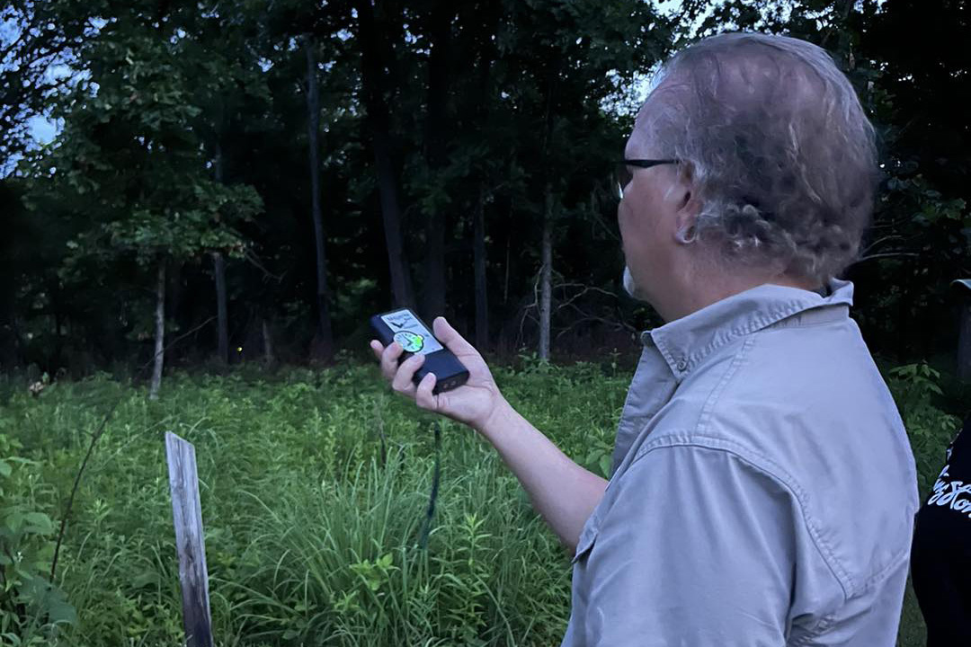 A man holds a sound tracker in the woods