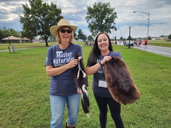 Two woman hold animal pelts
