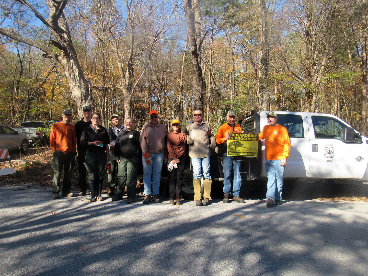 People in front of a truck in a forest wearing work clothes