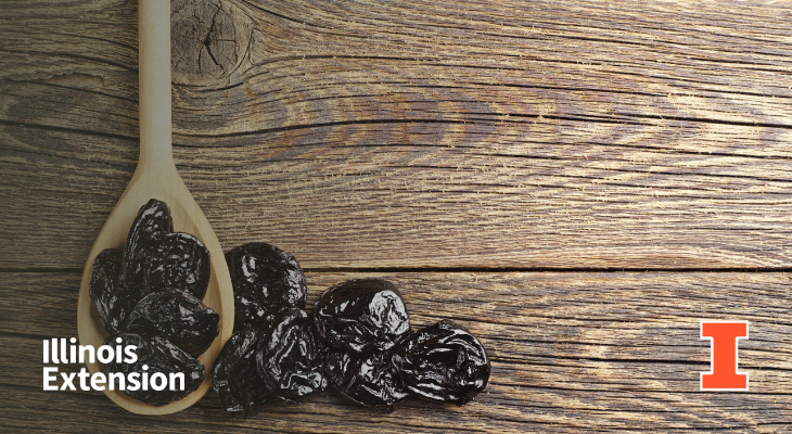 A wooden spoon with prunes along with prunes spilled on the table. Contains orange I block logo and Illinois Extension wordmark.