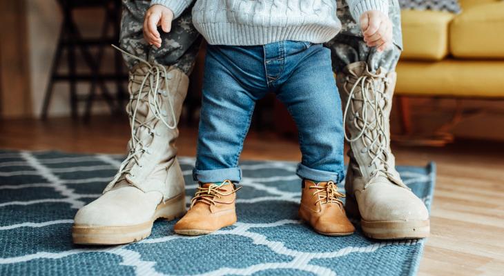view of someone in military boots standing behind child