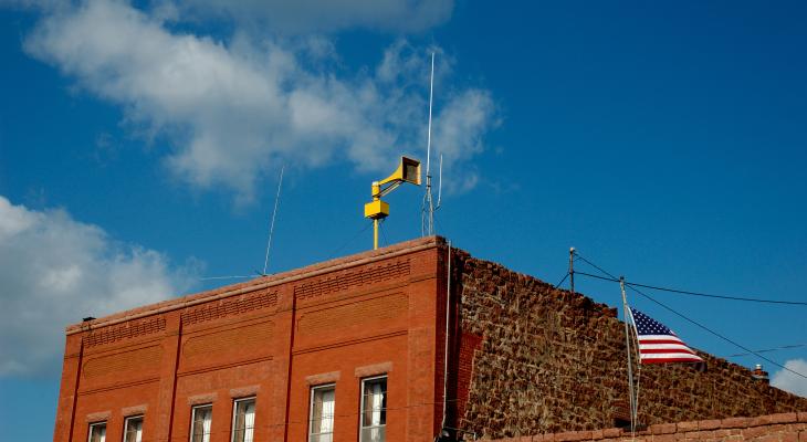 Yellow siren on roof of brick building