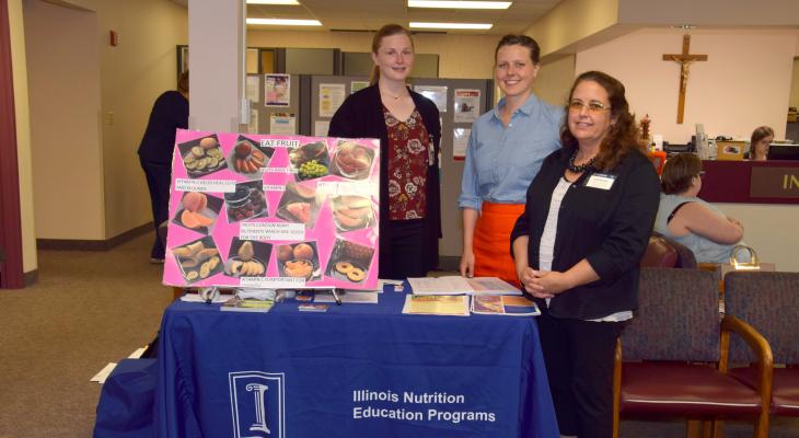 SNAP-Ed staff member with display booth with resources on healthy eating