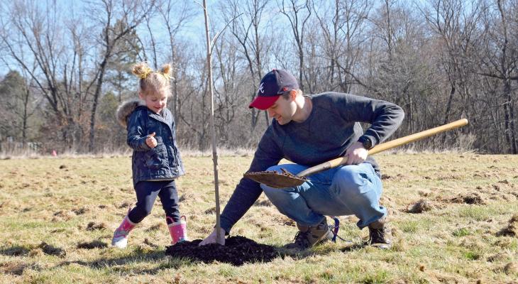 dad and daughter planting an oak tree