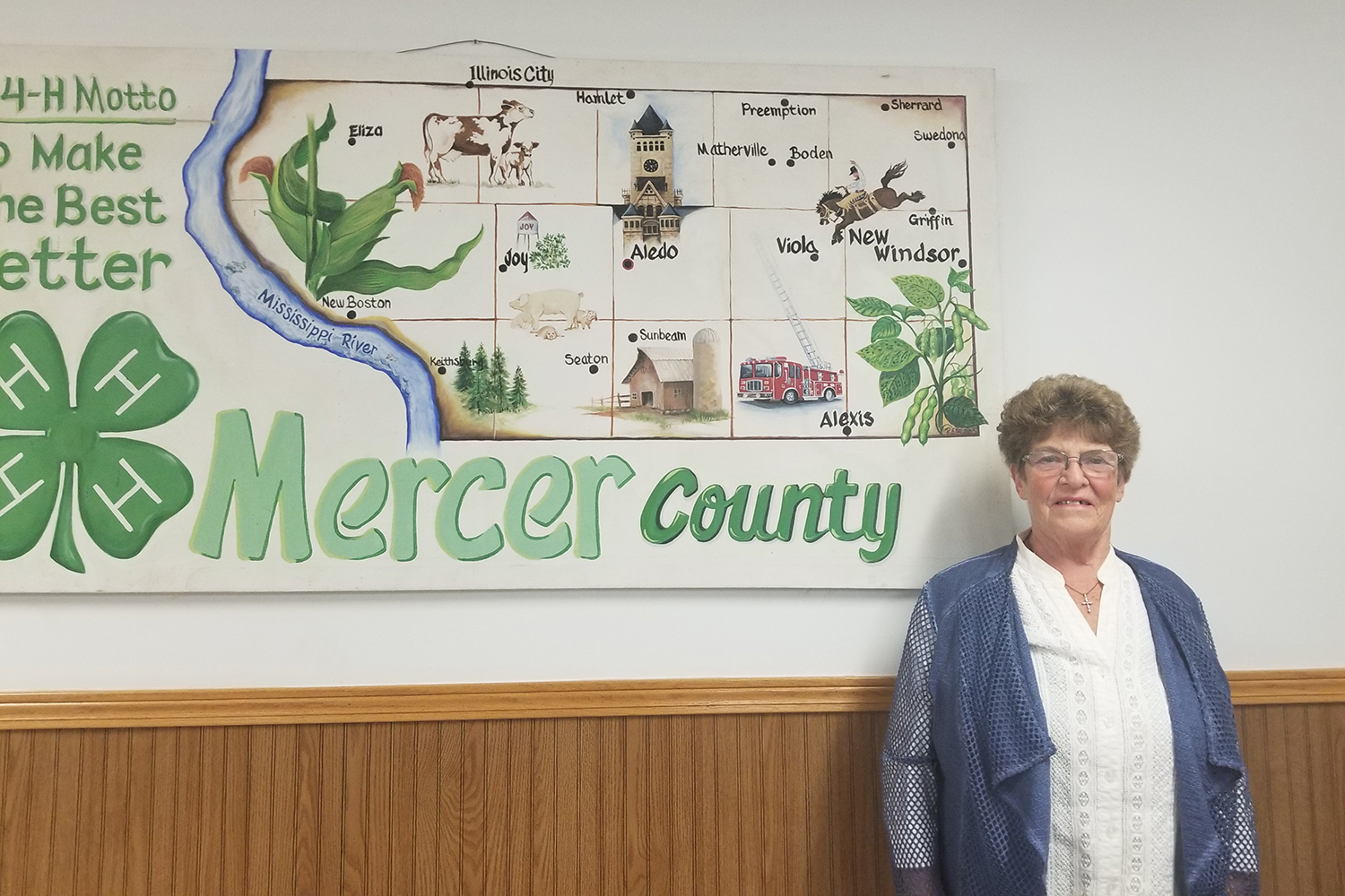 caucasian woman stands in front of map of Mercer County 4-H clubs