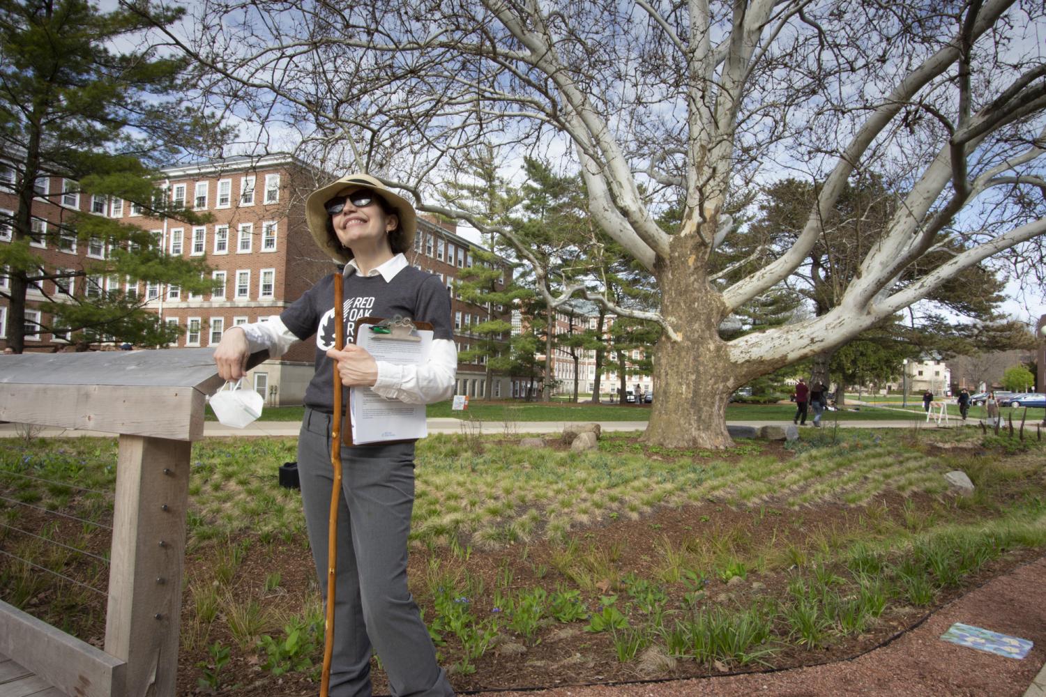Woman in hat and sunglasses stands in rain garden