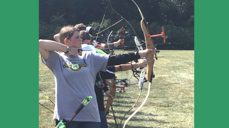 A group of youth doing archery in a field